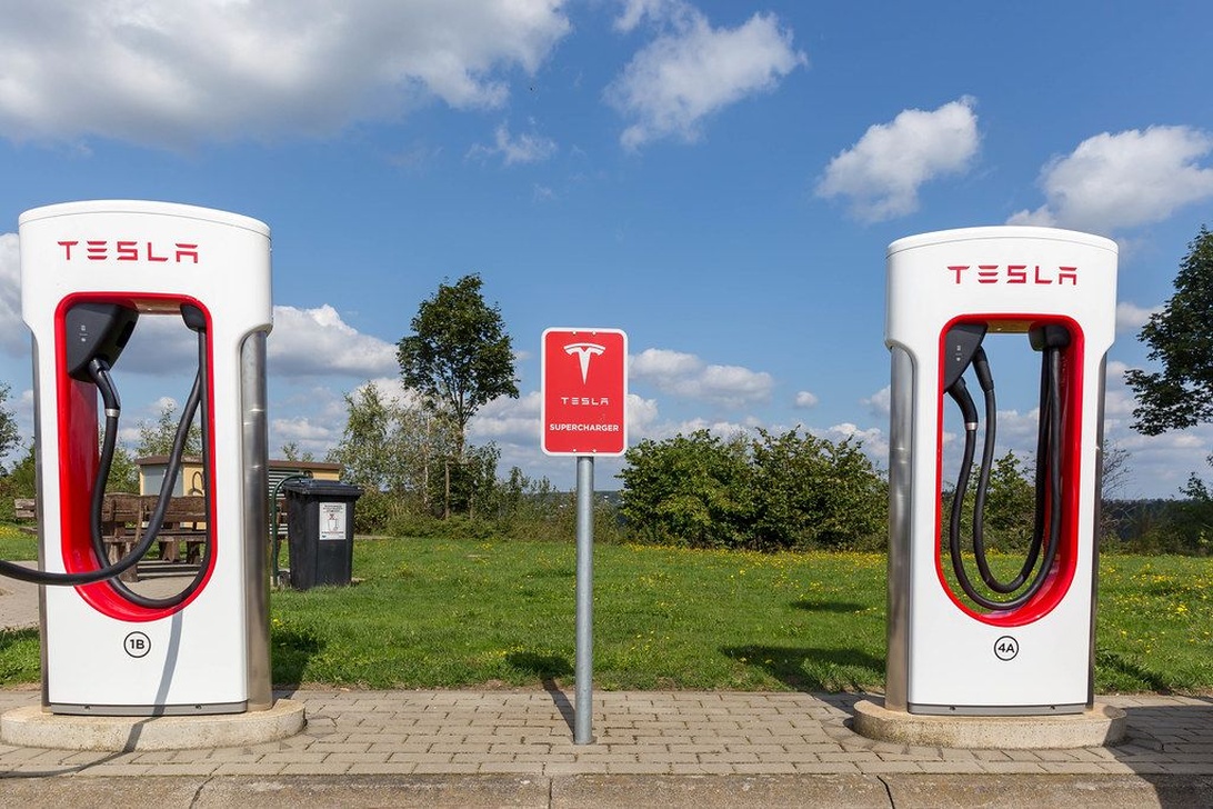 Två vita Tesla Supercharger-stationer med röda detaljer.